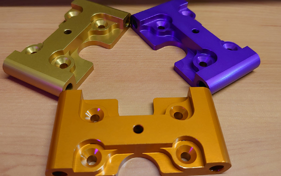 A picture of all three colours of front upper suspension arm mounts, our solution to replacing the plastic originals for extruded aluminium to provide more strength. Available in orange, purple and gold.