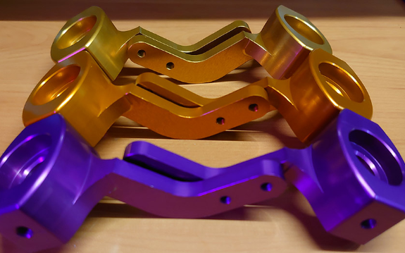 A picture of the three different colours of Front Hub Carrier pairs that we sell, provided in purple, orange or gold.